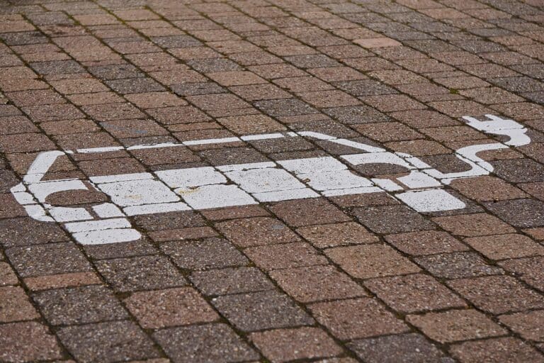 Bild lässt auf einen Parkplatz schließen. Auf den Pflastersteinen ist das Symbol für private batterieelektrische Fahrzeuge zu erkennen. MIt Stephan Rinderknecht habe ich über Elektromobilität gesprochen.