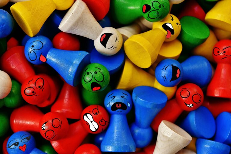 Das Bild zeigt viele bunte Spielsteine; eine Community. Die meisten Holzfiguren sind ohne Gesicht, doch ein paar haben eine Mimik aufgedruckt.